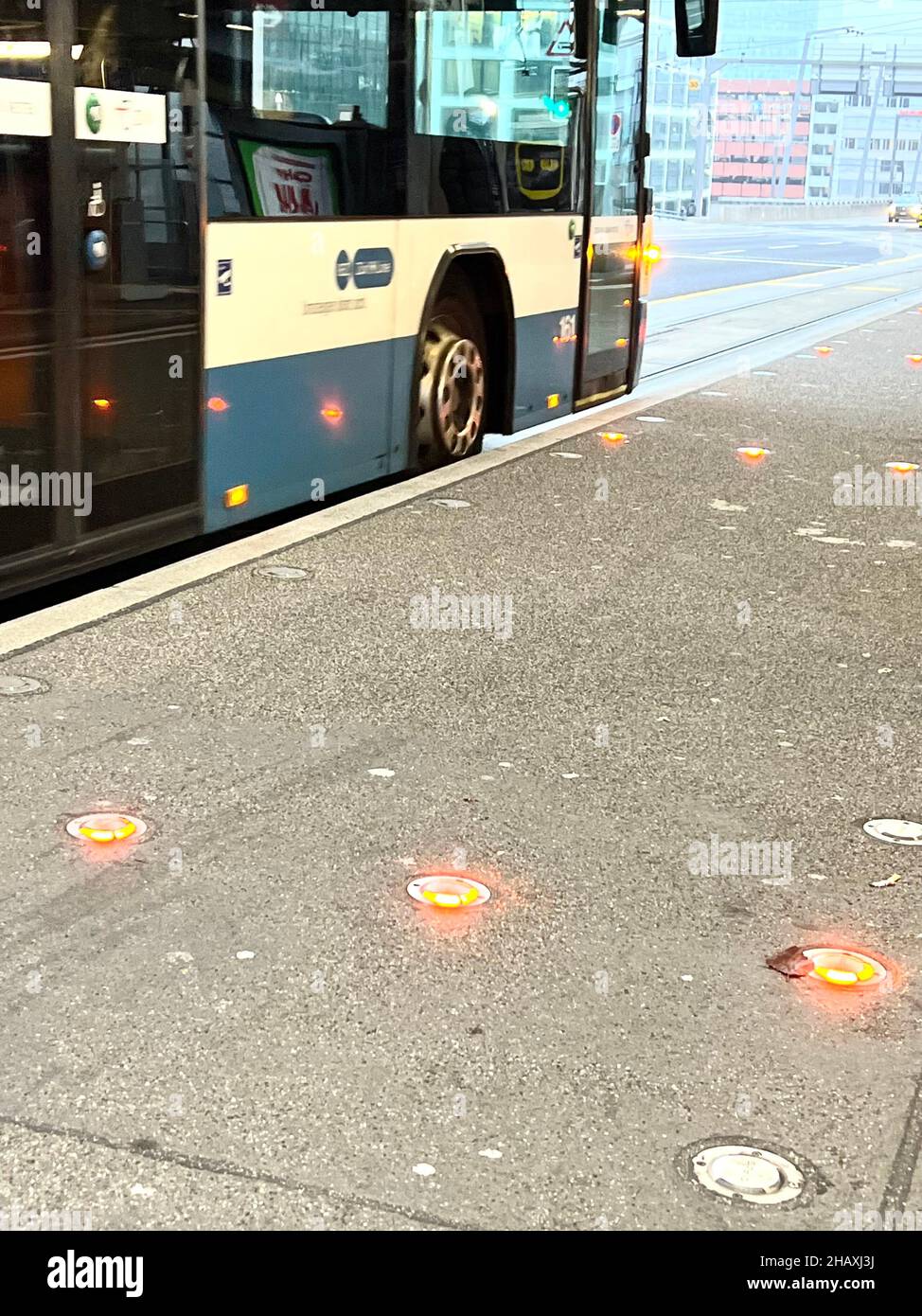 Öffentliche Verkehrsmittel Bus an der Bushaltestelle. Es gibt rote Lichter auf dem Boden, die verhindern, dass die Fahrräder auf dem Bürgersteig fahren, wenn es einen Bus gibt. Stockfoto