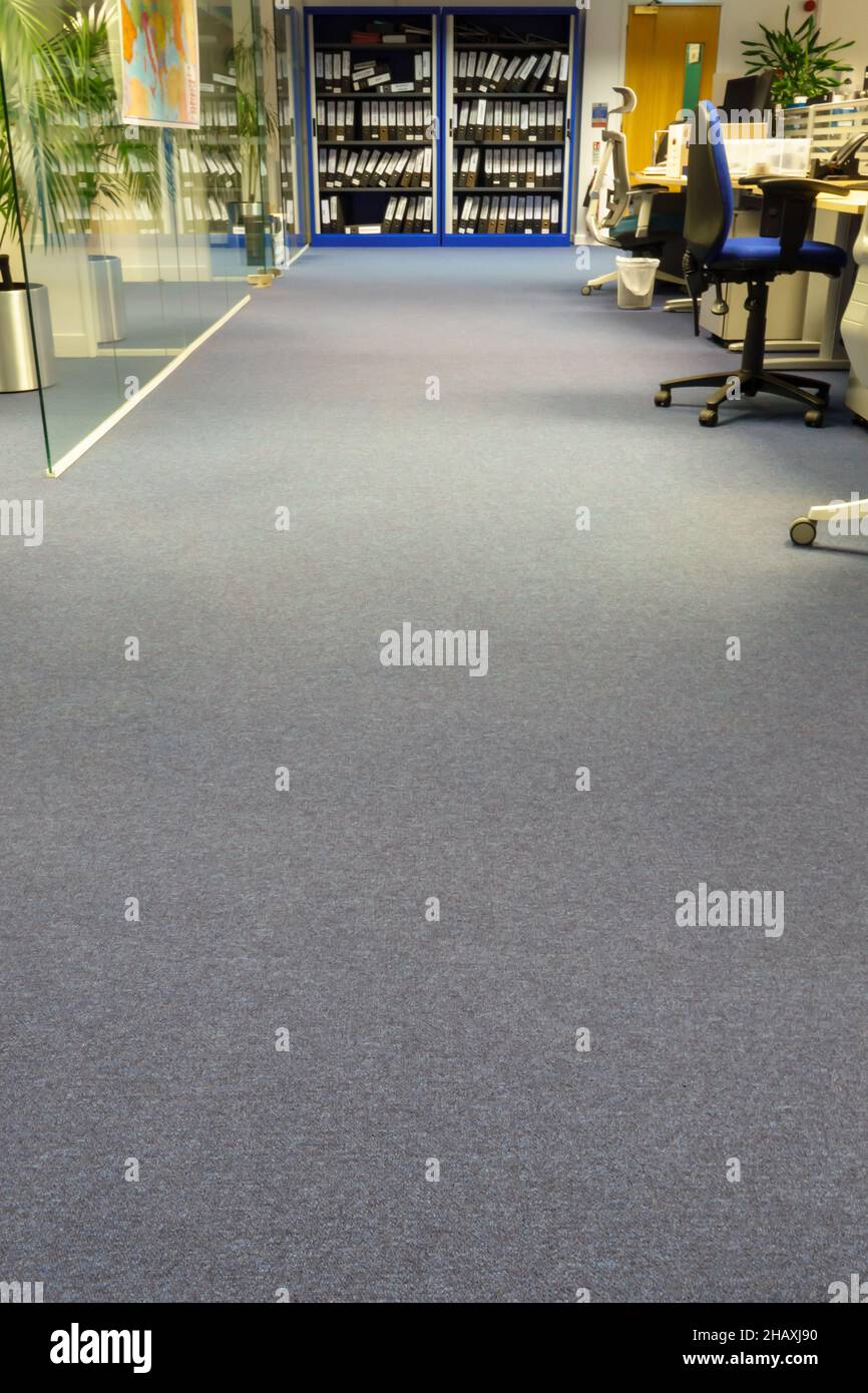 Blick durch den Raum mit Schreibtischen, Stühlen, Bildschirmen und Aktenschränken in einem leeren, offenen Büro Stockfoto