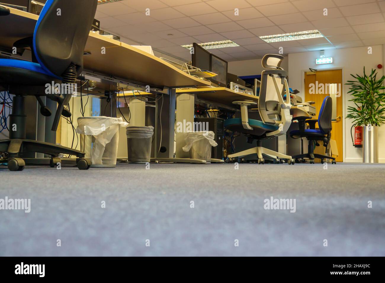 Blick vom Boden auf Schreibtische, Stühle und Bildschirme in einem leeren Großraumbüro Stockfoto