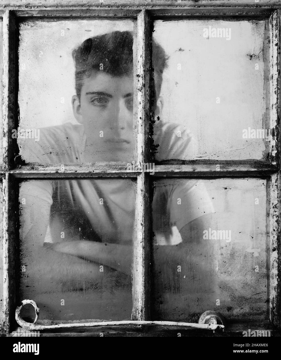 Junge Model schaut durch das Fenster mit Regen Stockfoto