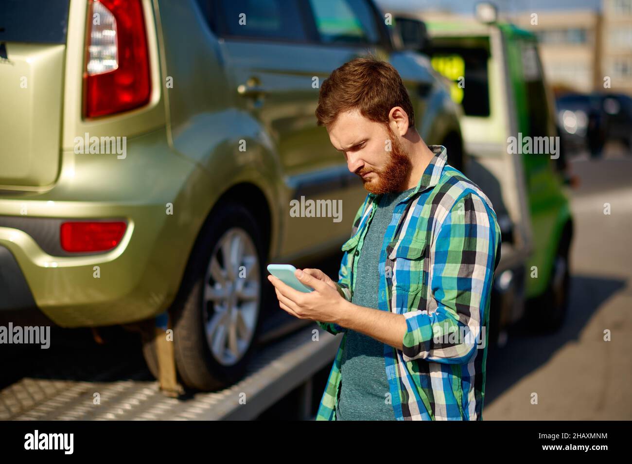 Mann ruft an, während der Abschleppwagen das Auto abholt Stockfoto