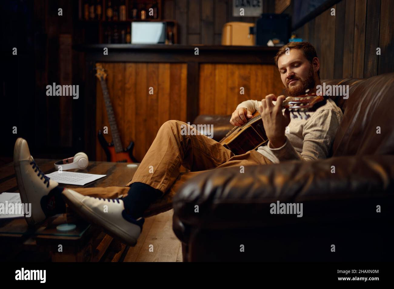 Gitarrist, der zu Hause auf der Couch trainiert Stockfoto