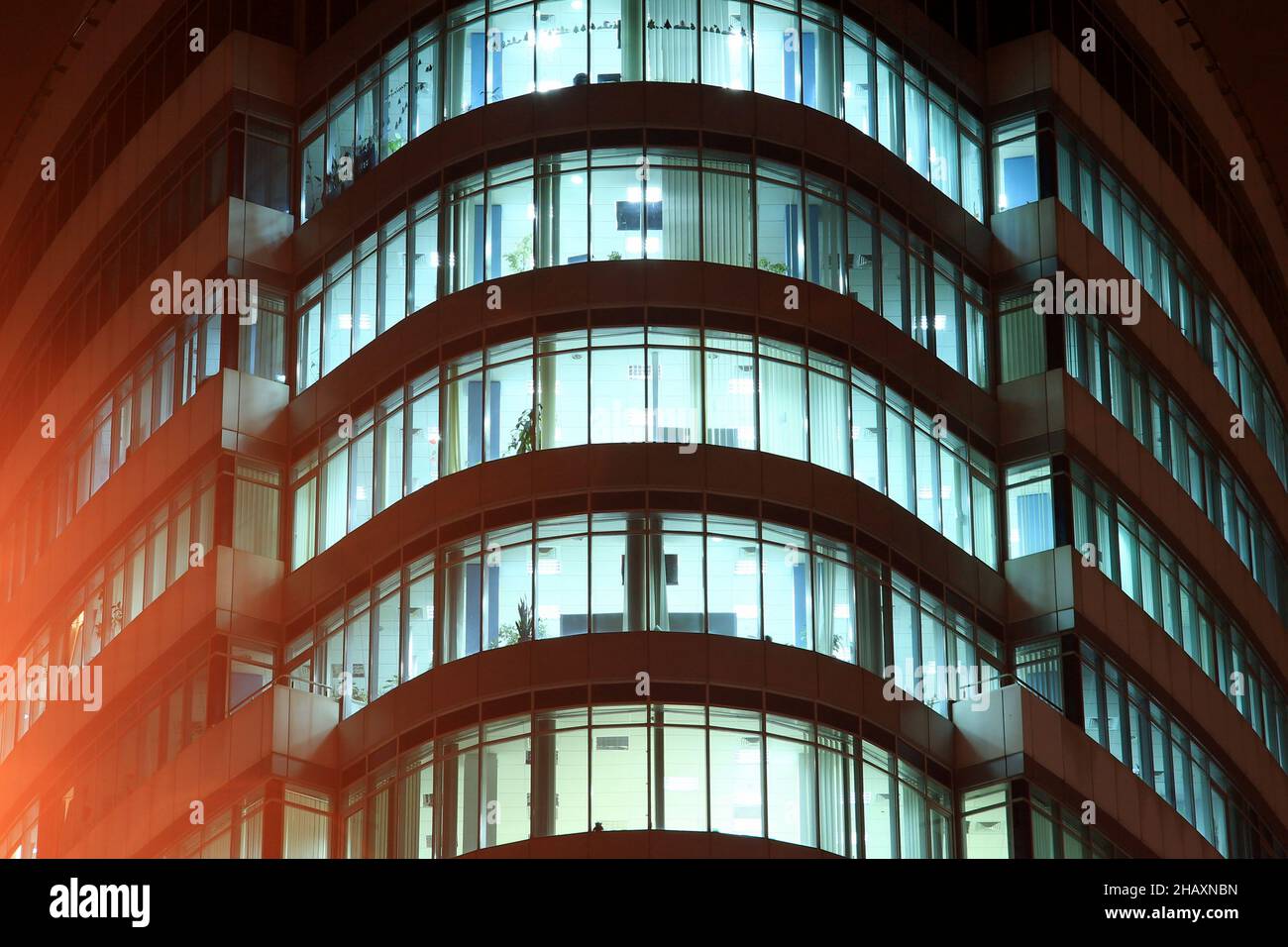 Die Fassade eines runden Glasgebäudes mit großen Panoramafenstern und Balkonen in der Nacht, die Fenster leuchten im Dunkeln. Dnipro City, Dnepr, Ukraine Stockfoto