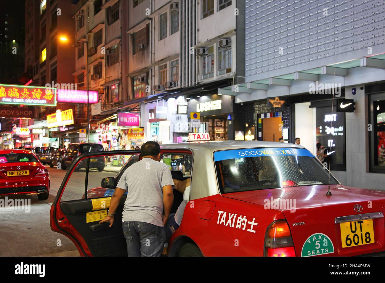 Ein Mann, der nachts in Tsim Sha Tsui East, Kowloon, Hongkong, in ein Taxi fährt. Stockfoto