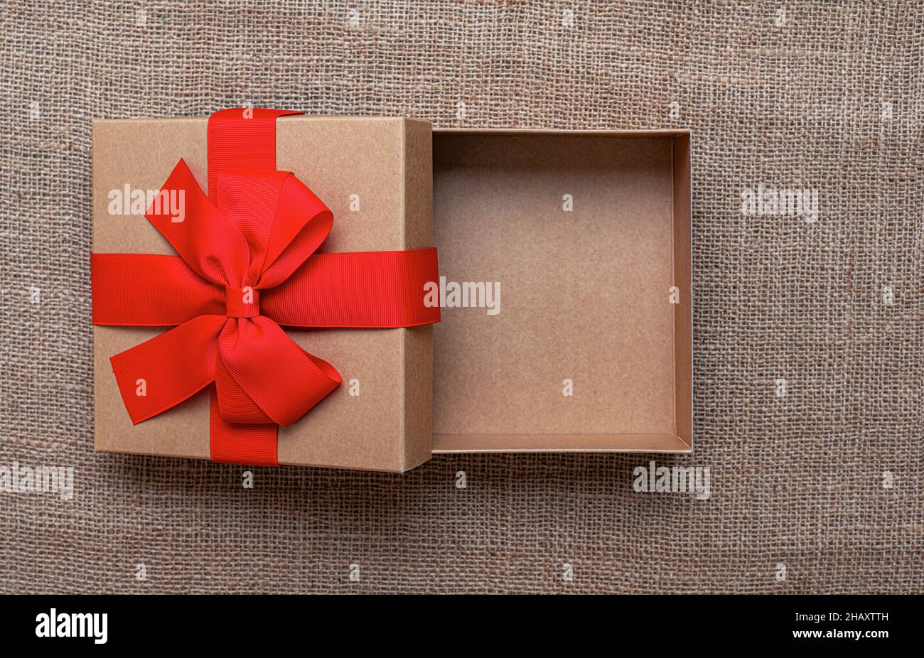 Die Geschenkbox liegt auf einem Sackleinen Hintergrund. Stockfoto