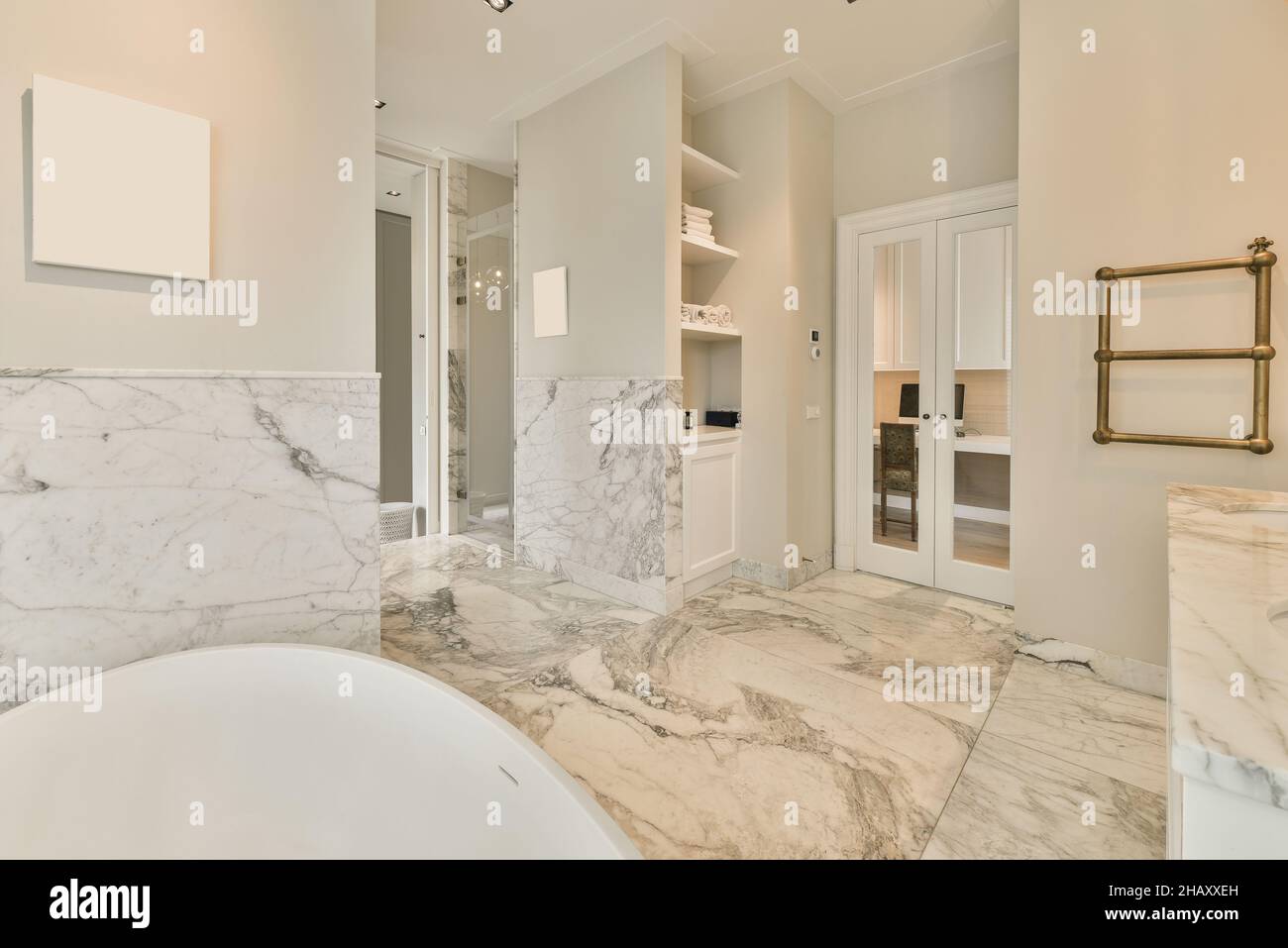 Innen gefliestes Badezimmer mit Badewanne und beheiztem Handtuchhalter aus Bronze und eingebauten Regalen Stockfoto