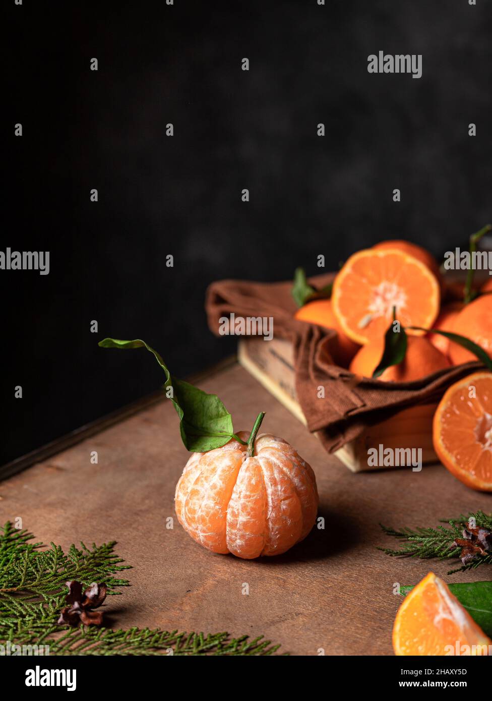 Draufsicht Haufen von frischen orange Mandarine mit Blättern in Behälter mit Textil auf Tisch mit grünen Zweigen im Raum platziert Stockfoto