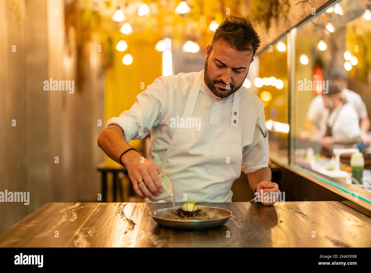 Mann gießt flüssigen Stickstoff aus Soße Boot auf Teller mit Seeigel in Molecular Cuisine Restaurant Stockfoto