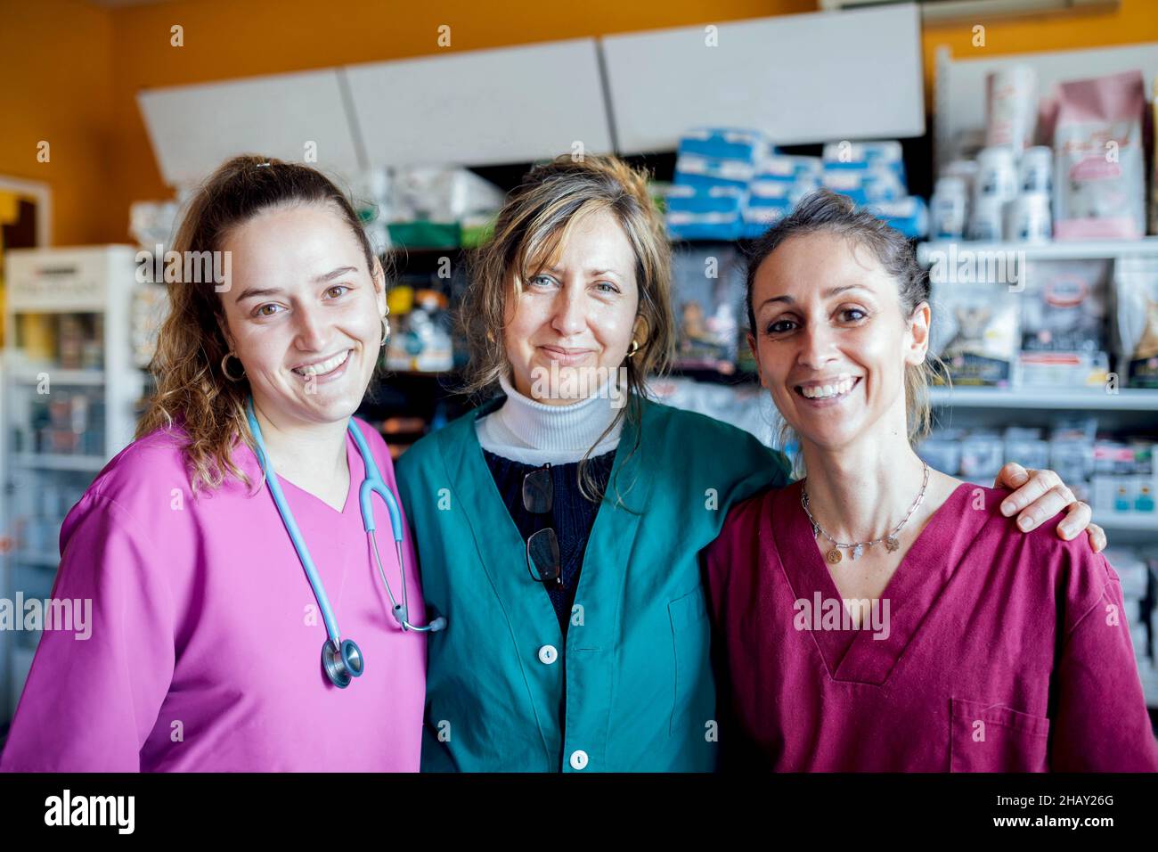 Gruppe positiver Tierärztinnen in Uniformen, die während der Arbeit in der Tierklinik mit medizinischen Hilfsgütern auf die Kamera schauen Stockfoto