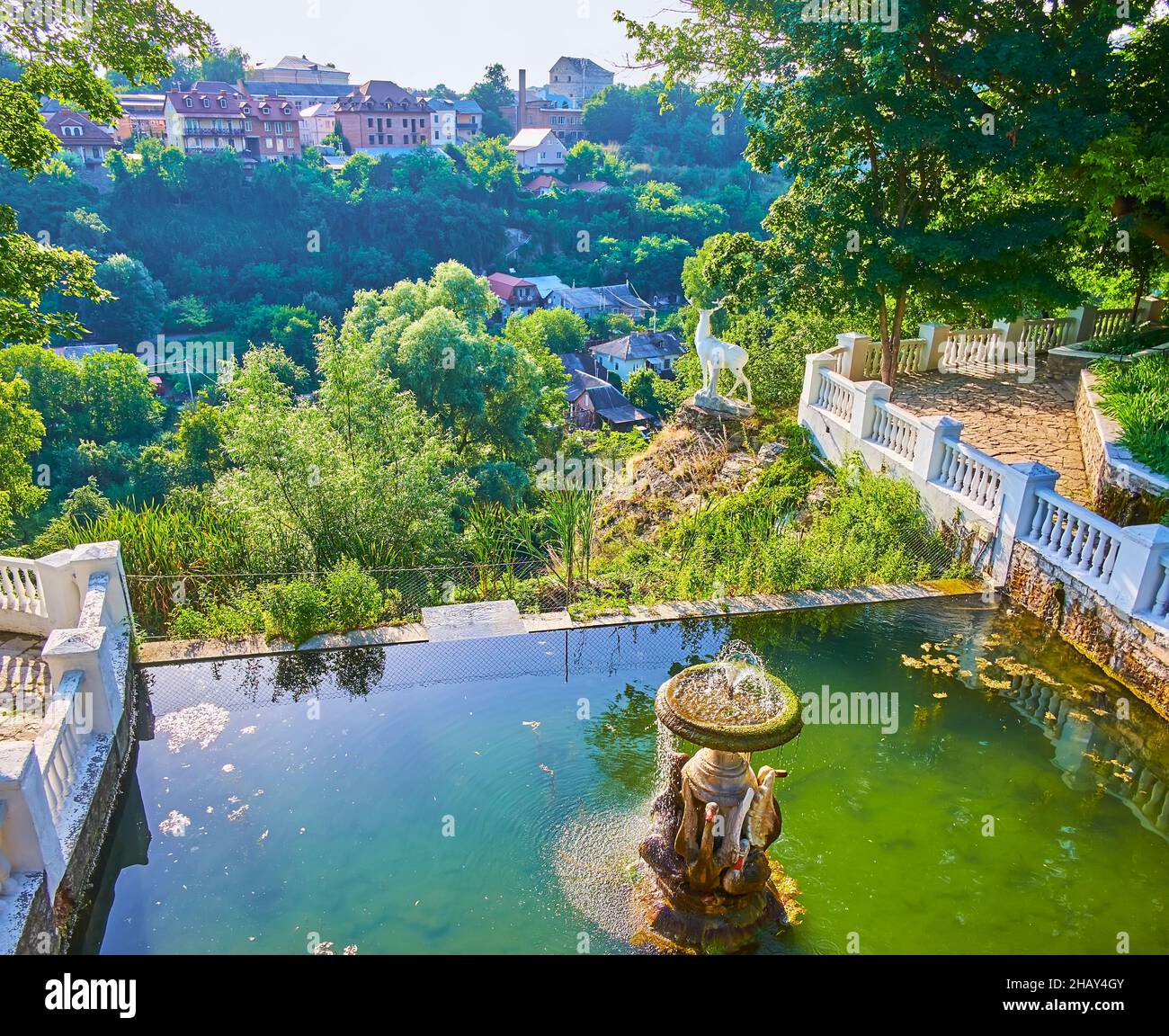 Der Blick von oben auf den Schwanensee mit einem Brunnen und das üppige Grün des Smotrych River Canyon im Hintergrund, Kamianets-Podilskyi, Ukraine Stockfoto