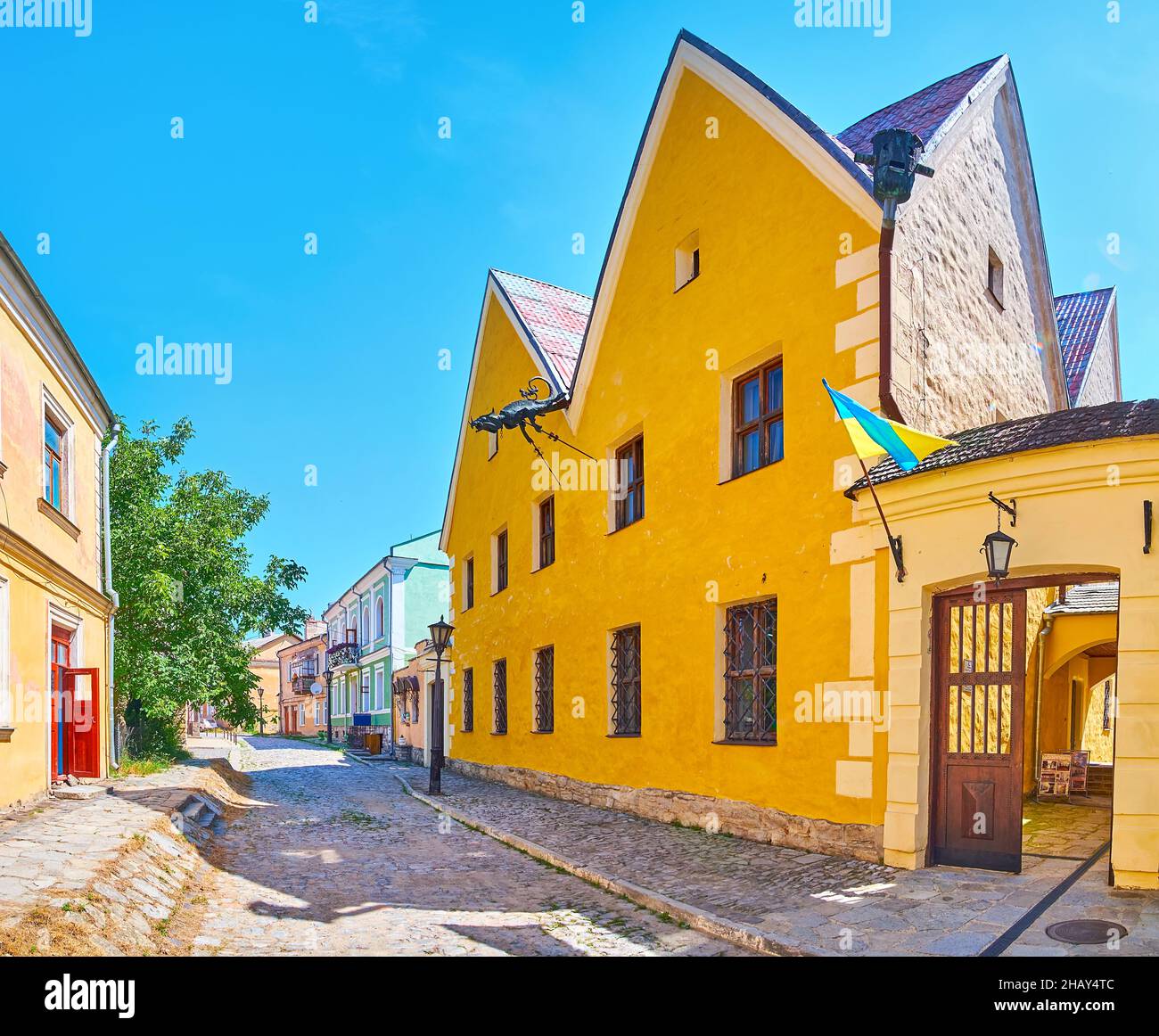 Die schmale Steinstraße Pyatnytska mit historischem Gehäuse und einem leuchtend gelben Gebäude des russischen Magistrat, geschmückt mit dem drachenförmigen Wasserspeier Kami Stockfoto