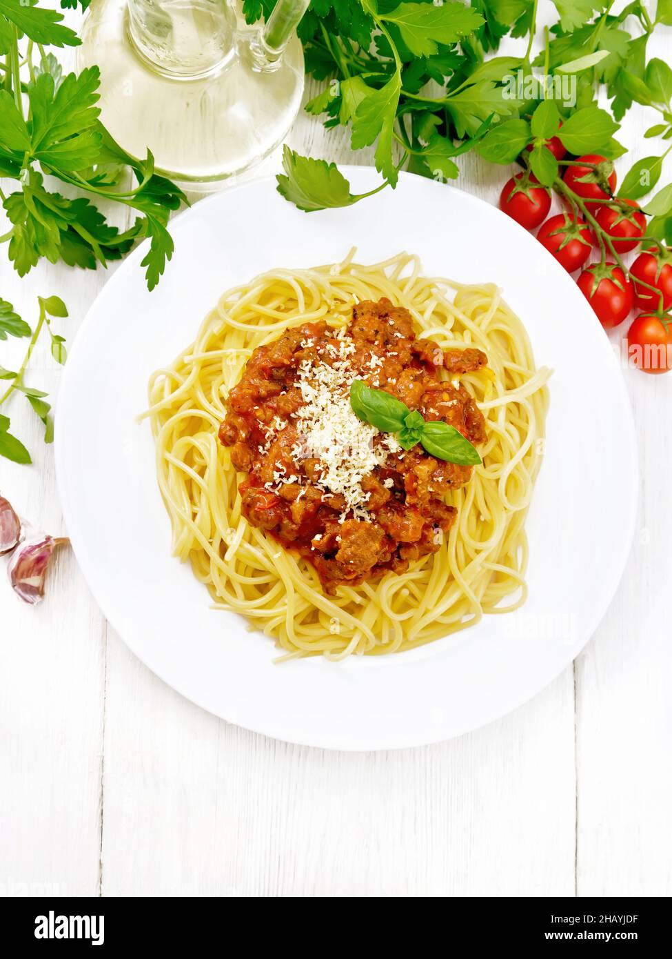 Spaghetti mit Bolognese-Sauce aus Hackfleisch, Tomatensaft, Knoblauch, Wein und Gewürzen mit Käse auf einem Teller, Pflanzenöl, würziges Kraut auf einem Seufzer Stockfoto