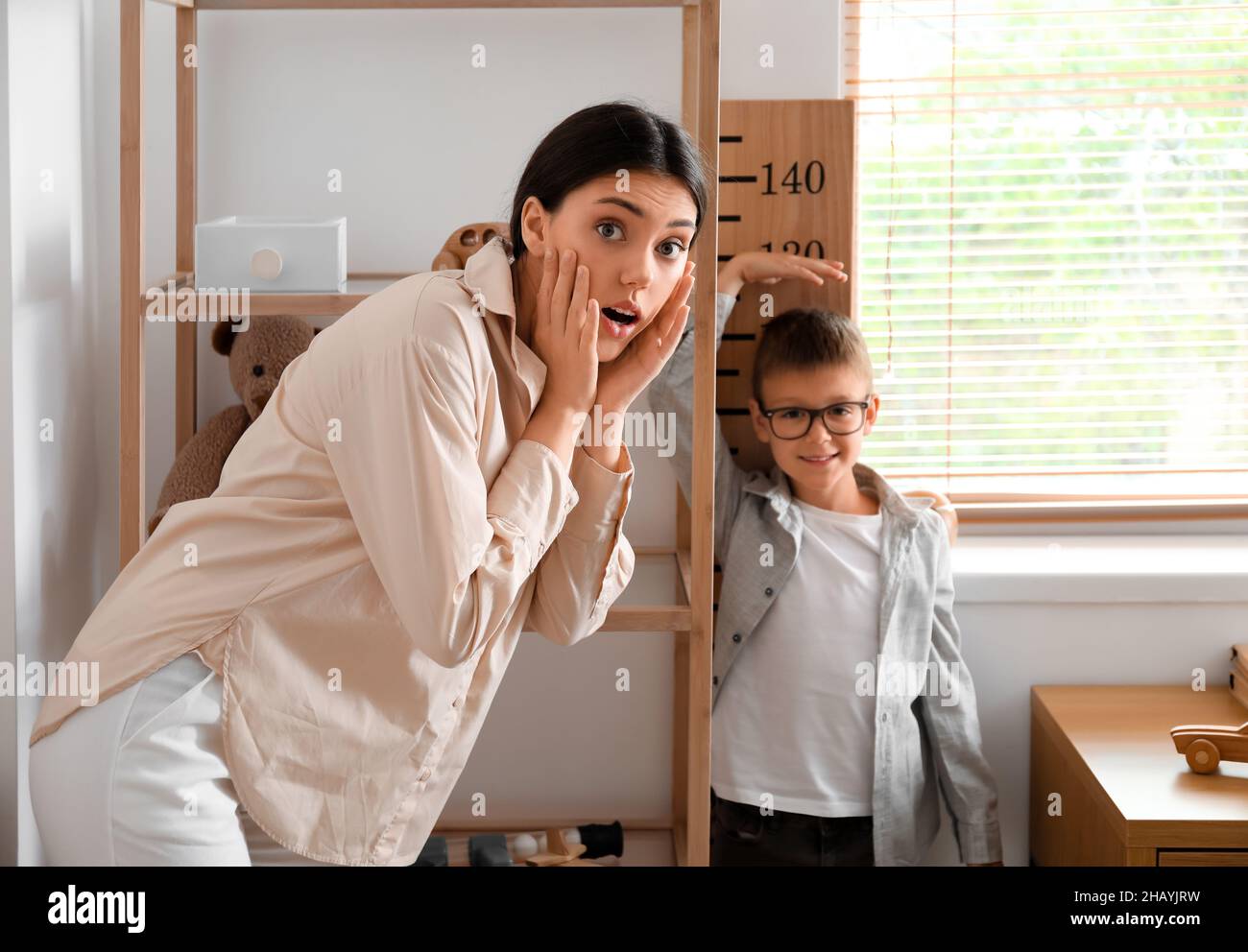 Kleiner Junge, der die Höhe misst, und seine ältere Schwester zu Hause schockiert Stockfoto