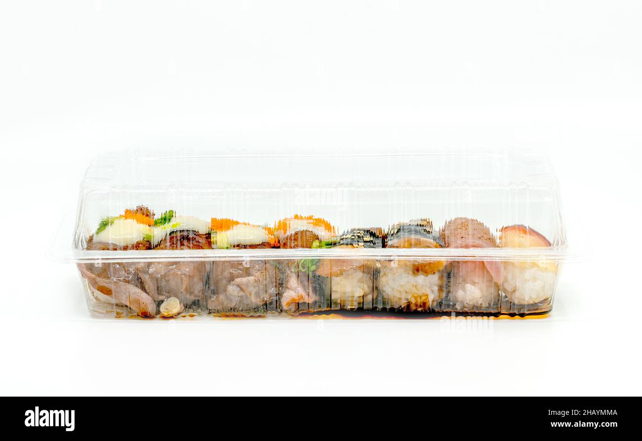 Nahaufnahme verschiedener Sushi-Typen in der zum Mitnehmen abgeräumten Lebensmittelbox, in der langformigen Lebensmittelbox, Vorderansicht Sushi in einer abgeräumten Verpackung auf weißem Hintergrund Stockfoto
