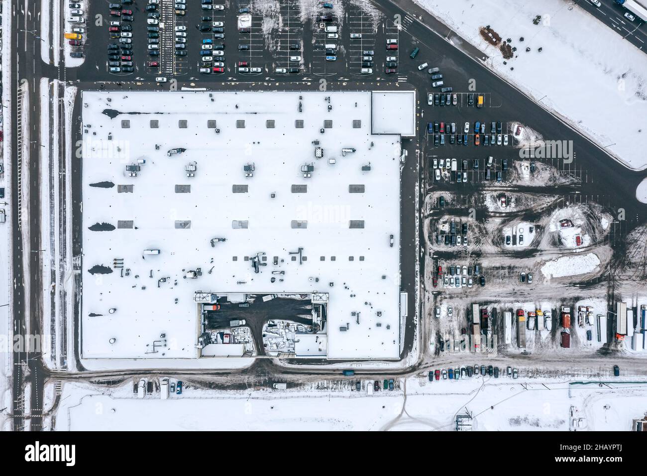 Parkplatz im Freien mit vielen Autos in der Nähe des Einkaufszentrums im Winter. Luftaufnahme von oben. Stockfoto