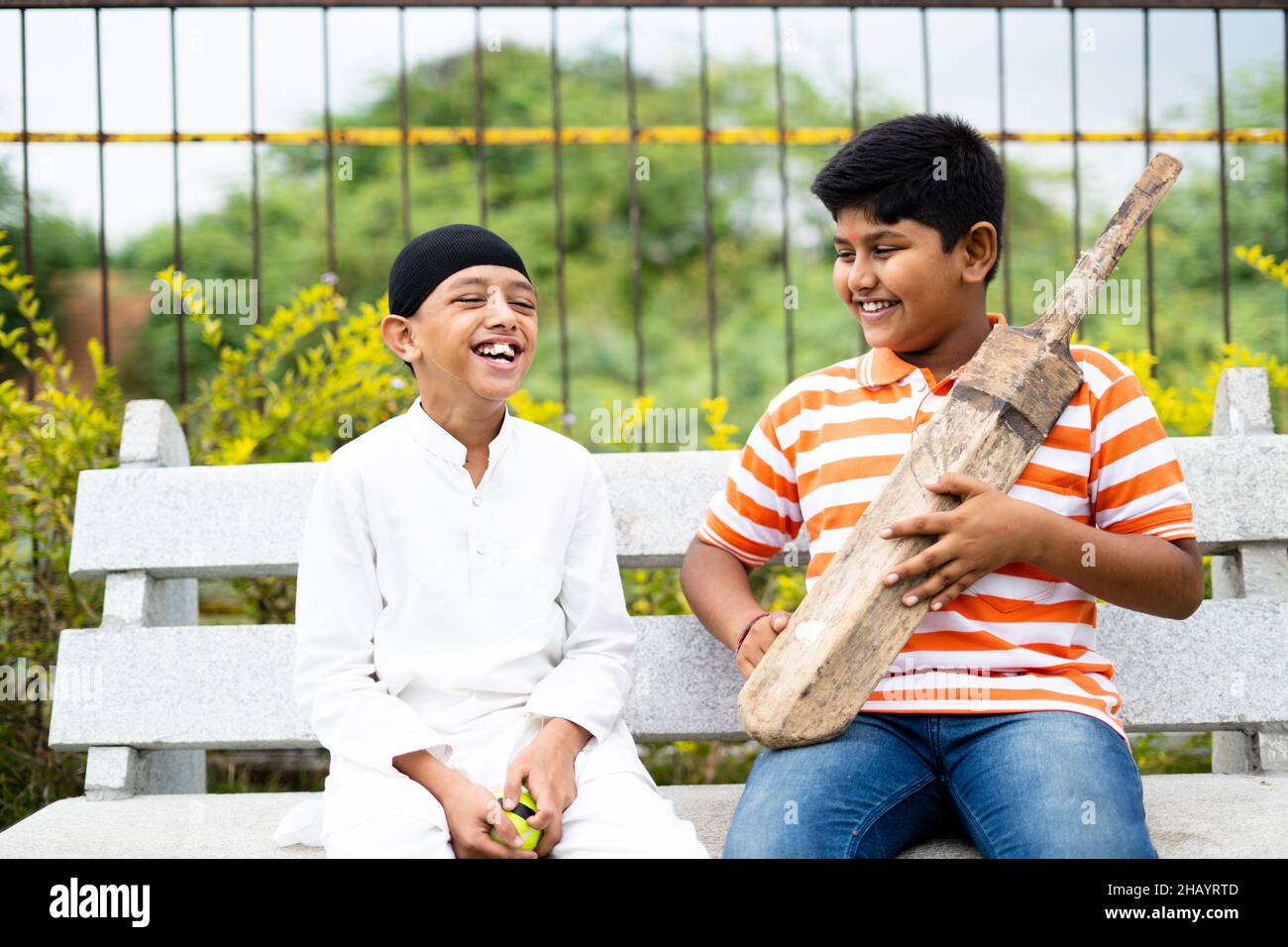 Glückliche indische multiethnische Kinder sprechen über Cricket mit Fledermaus und Ball sitzen im Park - Konzept der Kindheit Freundschaft, Urlaub, Urlaub Stockfoto