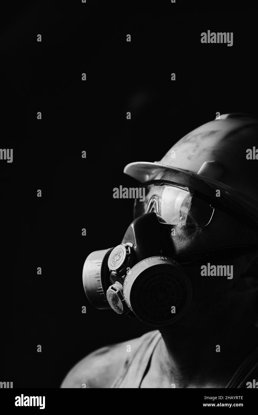 Profil Portrait Bergmann in Helm, Atemschutzmaske und Brille, Blick auf Licht.schmutzige Arbeiter im Hemd Stockfoto