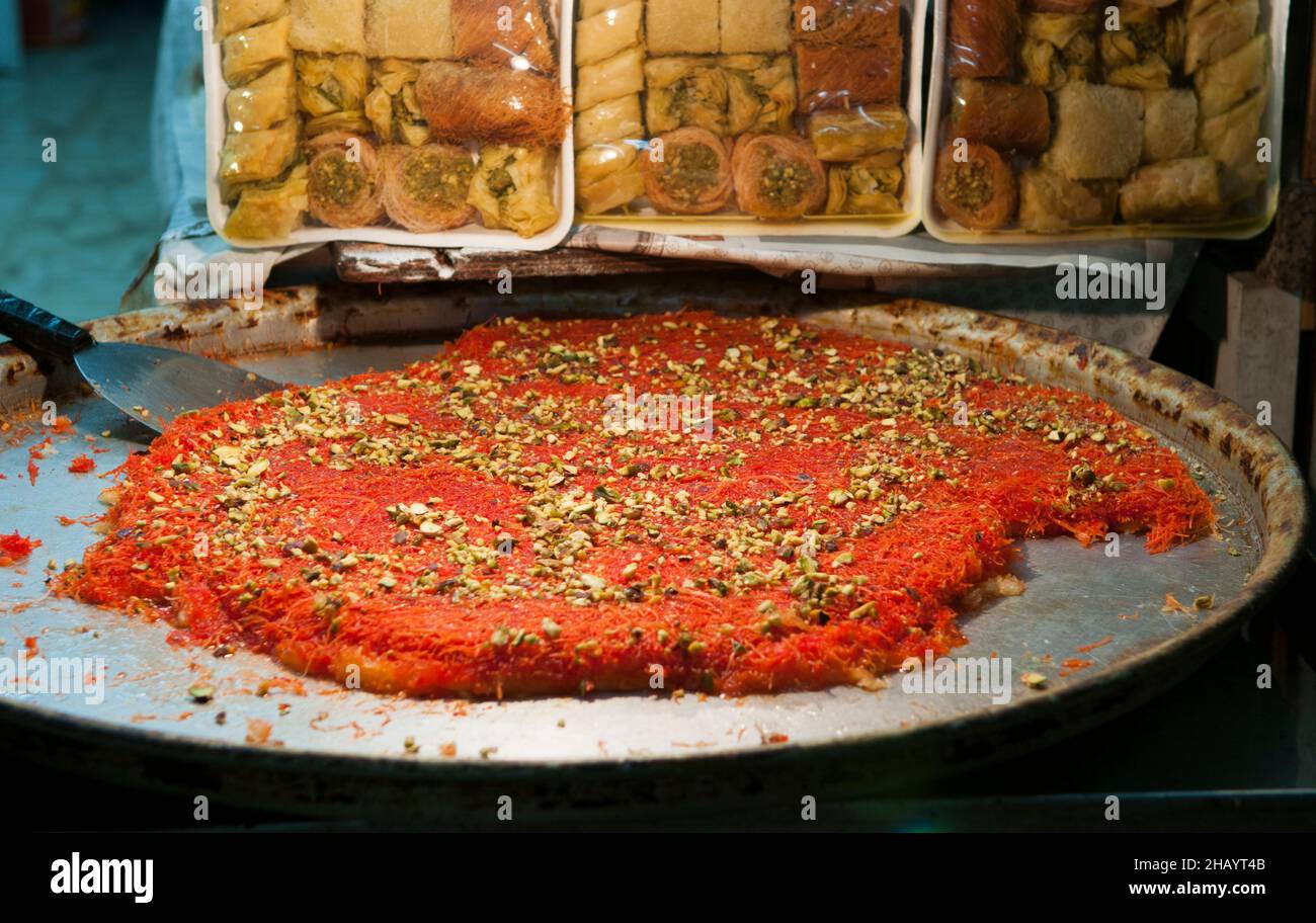 Knafeh ist ein traditionelles Dessert aus dem Nahen Osten, das aus gesponnenen Backwaren namens Kataifi hergestellt wird, die in süßem Zuckersirup getränkt und in der Regel mit Käse übereinander gelegt sind. Stockfoto