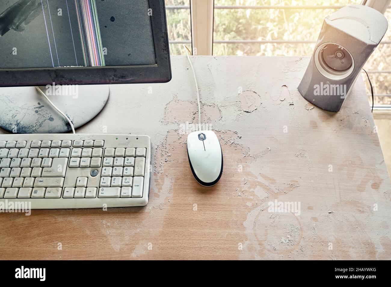 Alte Tastatur mit Maus und kaputtem Monitor stehen auf einem Holztisch und sind in einer Werkstatt mit dickem Staub bedeckt. Draufsicht Stockfoto