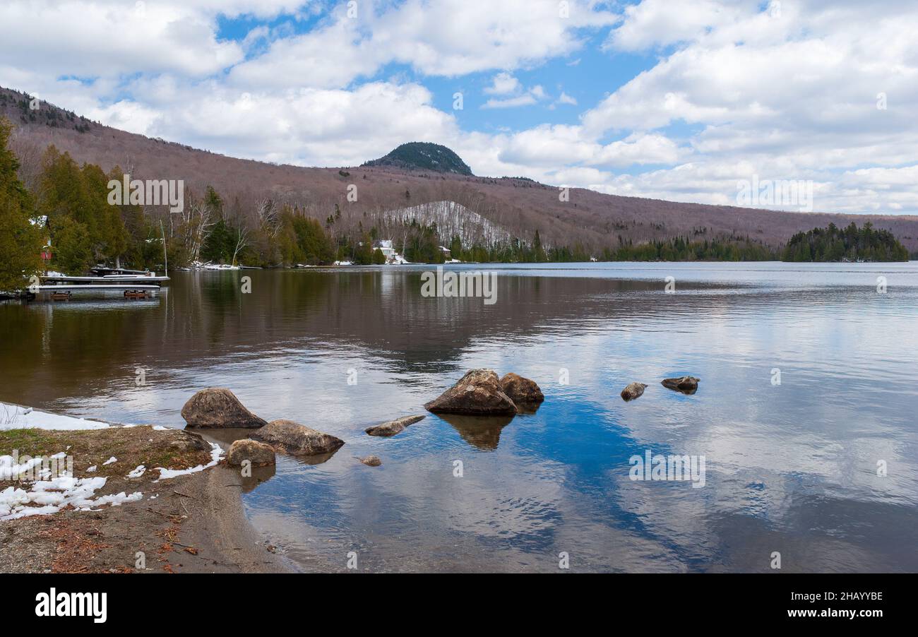 Blick auf den Long Pond im Frühling, mit dem Haystack Mountain im Rücken. Sommerhäuser entlang der Küste, in einer Waldlandschaft. Westmore, Vermont Stockfoto