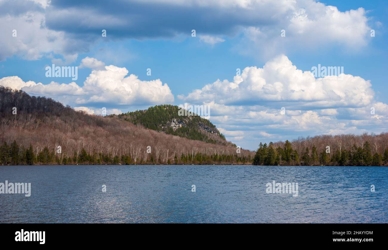 Spice Mountain - eine Granitklippe am Kettle Pond im Groton State Park, VT. Gemischter Birkenfichtenwald im Frühjahr. Cumulus-Wolken und Wellen das Wasser des Sees. Stockfoto