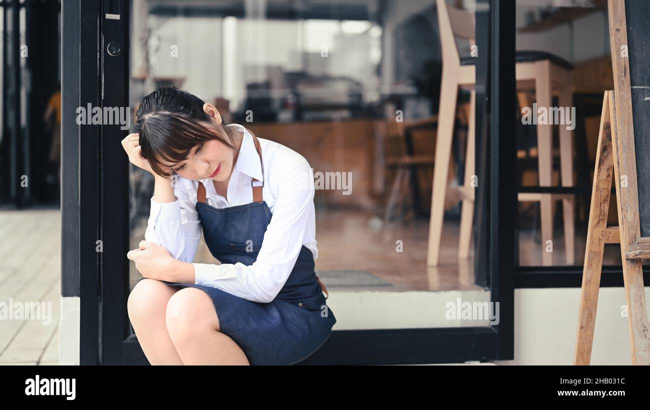 Gestresste Unternehmerin aus Kleinunternehmen, die vor ihrem Café sitzt. Stockfoto