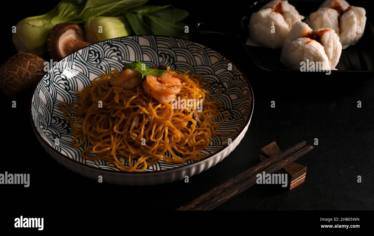 Köstliches Chow mein mit Garnelen auf einem Teller und gedämpften roten bbq-Schweinebraten. Konzept der chinesischen Küche Stockfoto