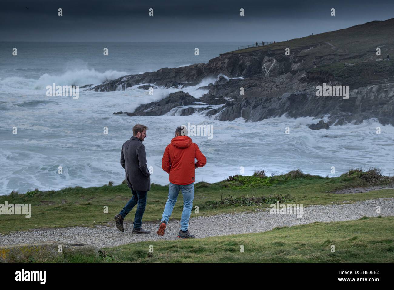 Menschen, die bei wildem Winterwetter den Küstenweg entlang gehen, an der Küste von Newquay in Cornwall. Stockfoto