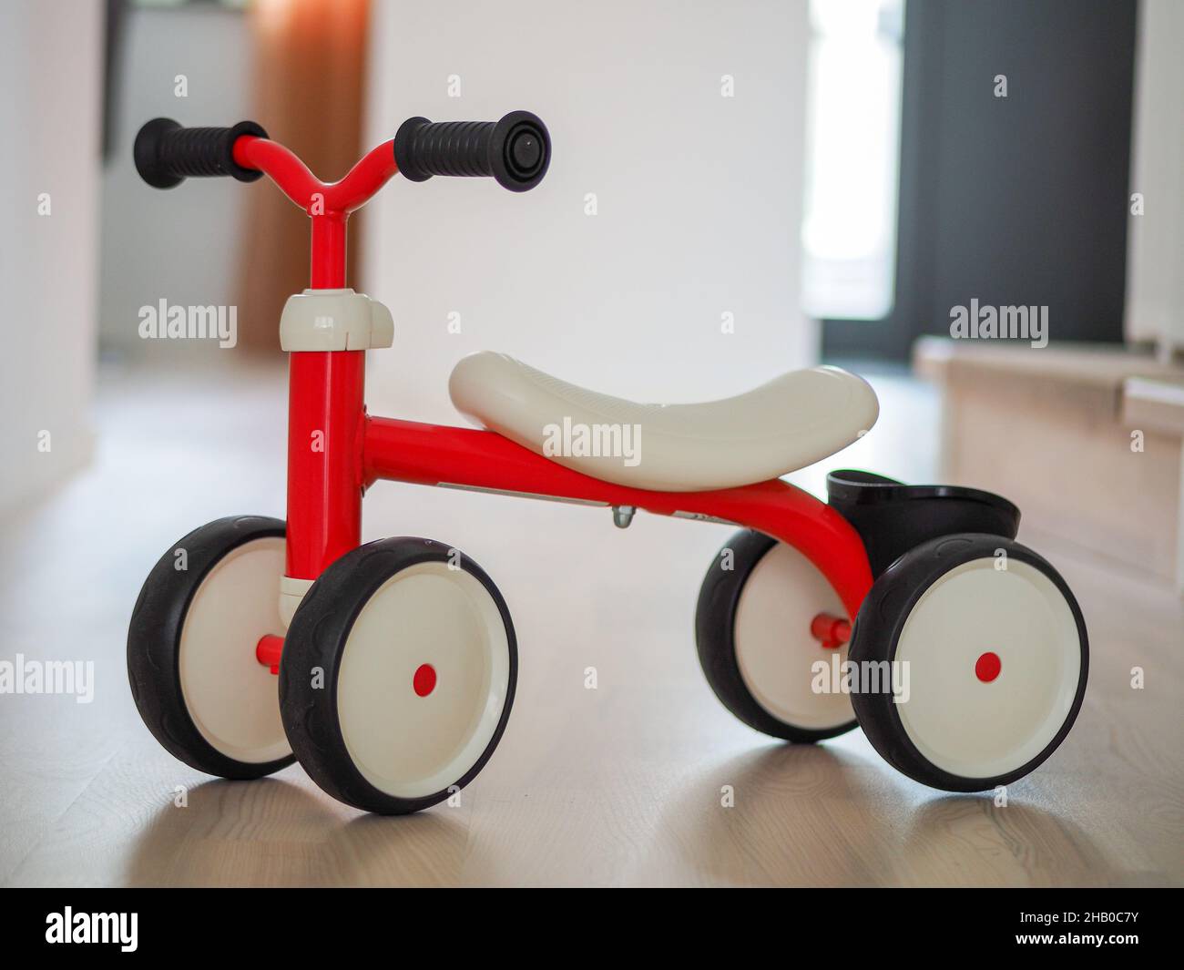 Kunststoff rot vierrädrigen Kinderfahrrad auf dem Holzboden Stockfoto