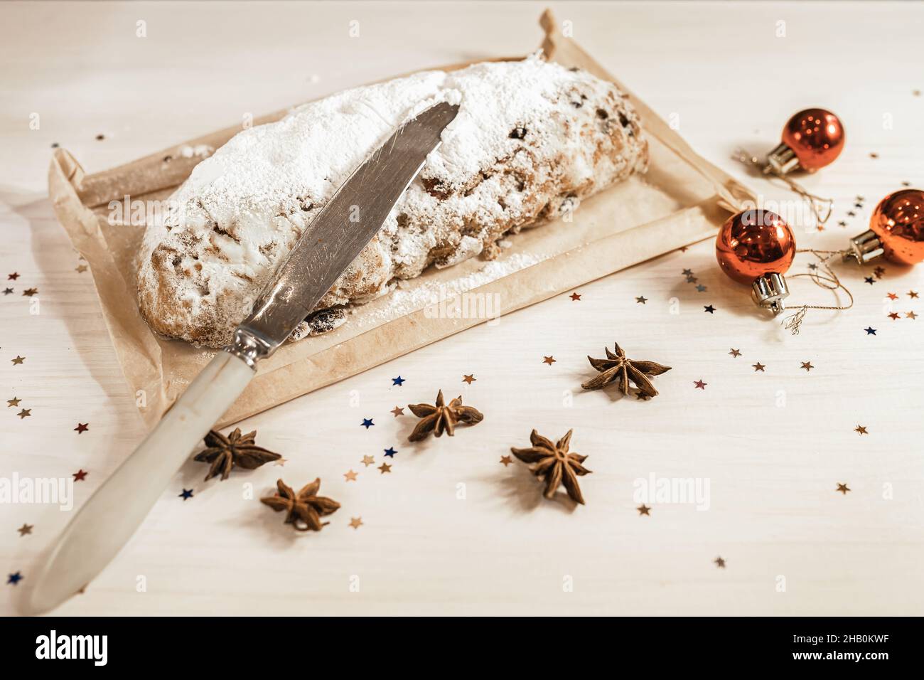 Stollen traditionelle Weihnachten deutsche Muffin Nahaufnahme und Schneidemesser auf Küchentisch mit verstreuten festlichen Lametta. Heiligabend. Stockfoto