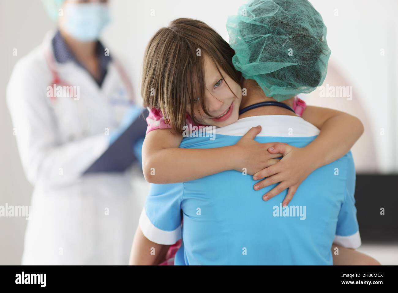 Das kleine Mädchen kletterte mit den Händen zum Arzt, um sich für die Hilfe zu bedanken Stockfoto