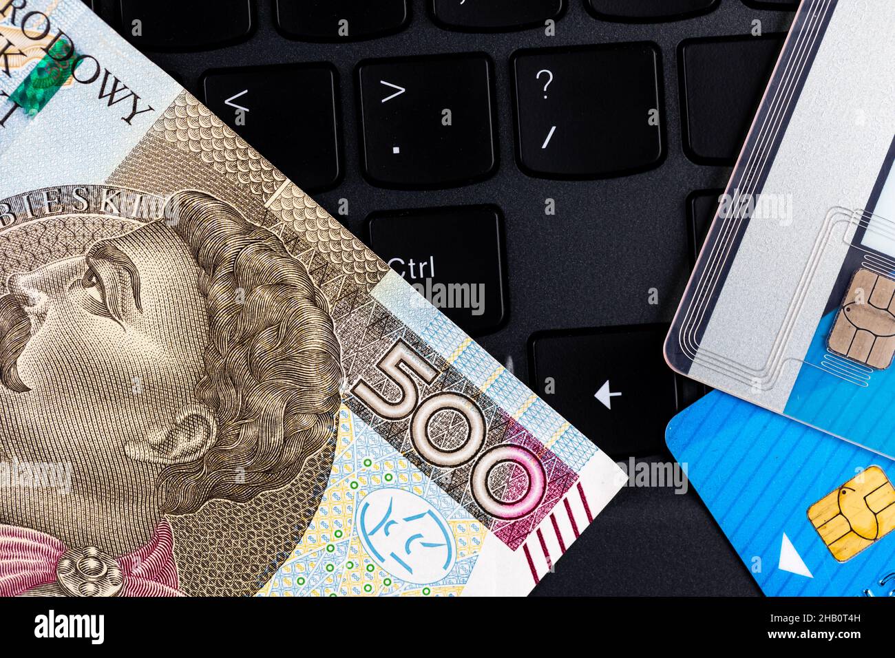 Polnische 500 PLN Banknote und Kreditkarten auf der Laptop-Tastatur angeordnet. Cybersicherheit des Online-Shoppings. Foto aufgenommen unter künstlichem, weichem Licht Stockfoto