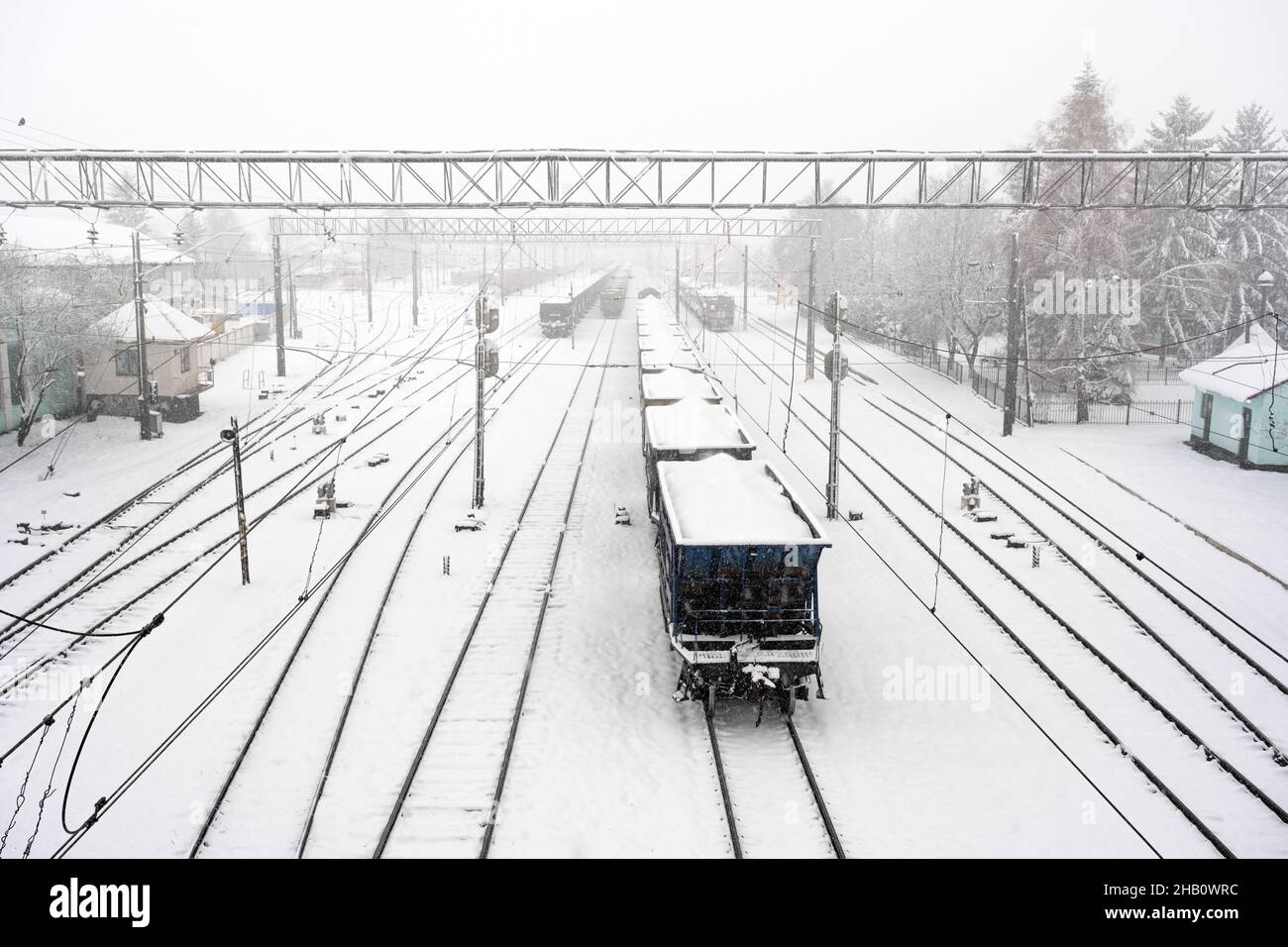 Bahnhof mit Eisenbahn im Winter von Schnee bedeckt. Güterwagen mit Kohle im Vordergrund. Ukraine, Europa Stockfoto