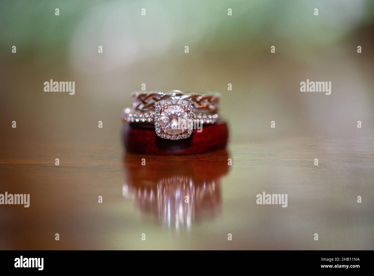 Hochzeitsring aus Weißgold mit Diamanten aus Kirschgold und Sandkirschgolden auf Holzoberfläche Stockfoto