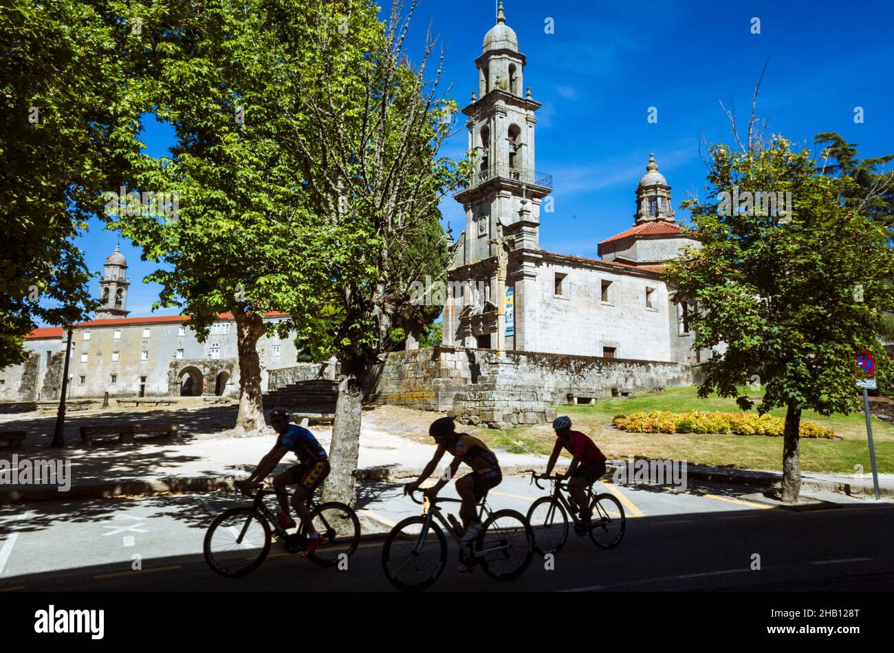 Allariz, Provinz Ourense, Galicien, Spanien : drei Männer radeln an der barocken Kirche San Benito vorbei. Stockfoto