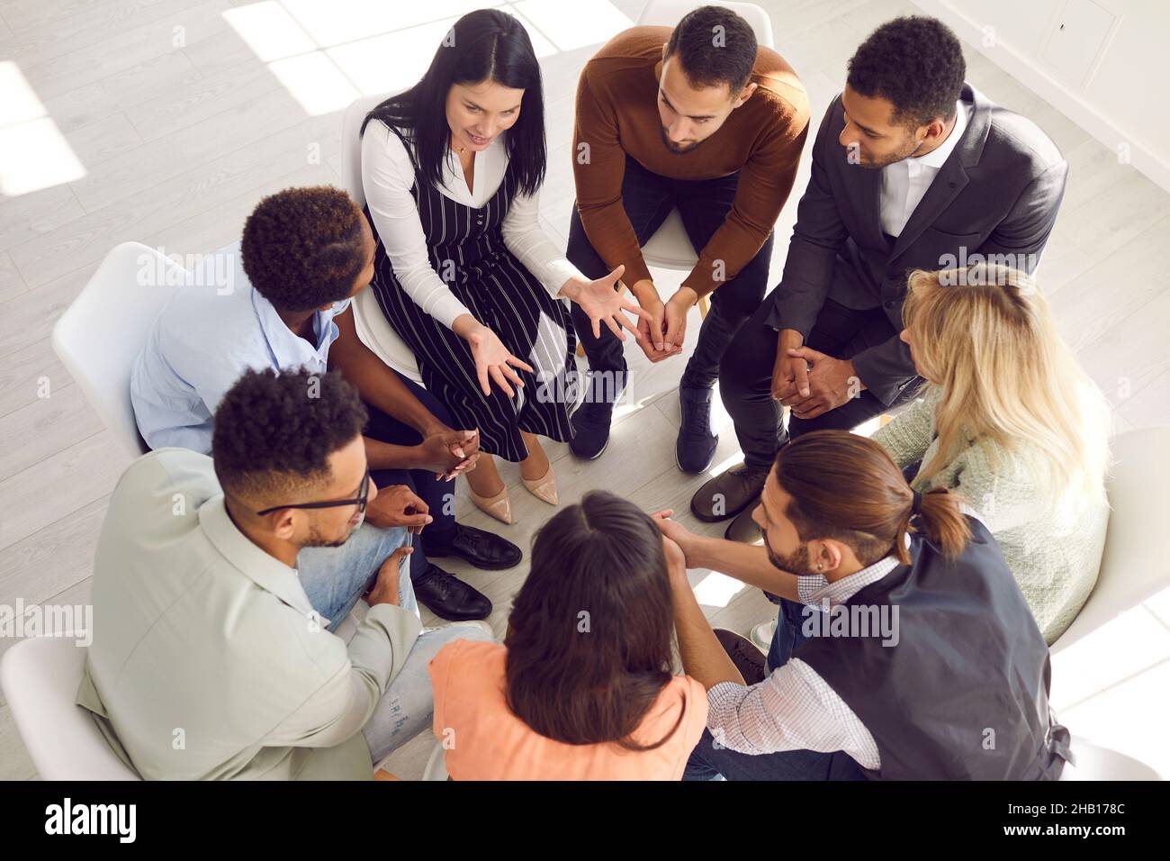 Verschiedene Menschen sitzen im Kreis, die sich mit Teambuilding-Aktivitäten beschäftigen Stockfoto