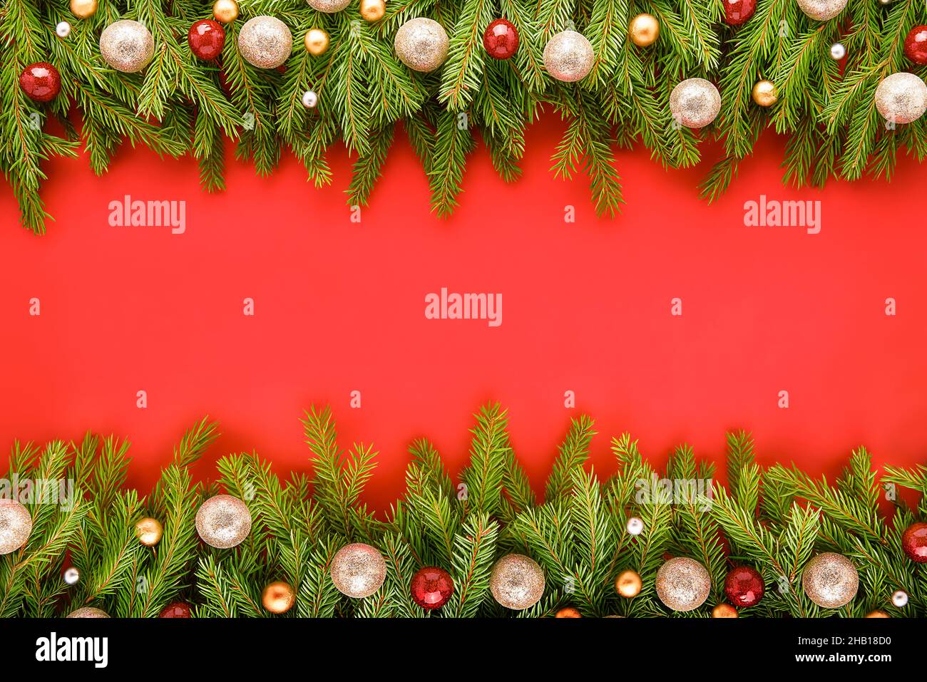 Weihnachtskarte. Weihnachtliche Dekoration auf Tannenzweigen vor einem leuchtend roten Hintergrund. Draufsicht, Platz für Text kopieren Stockfoto Weihnachtskarte. Weihnachtliche Dekoration auf Tannenzweigen vor einem leuchtend roten Hintergrund. Draufsicht, Platz für Text kopieren Stockfoto