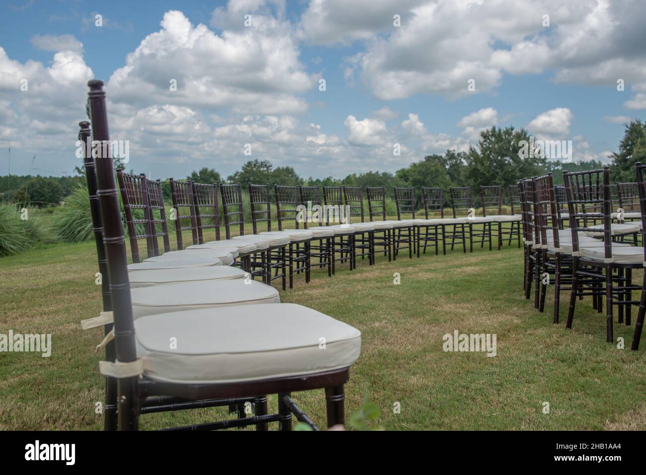 Einzigartige runde spiralförmige Hochzeitszeremonie mit Chairmustern in sanften Hügeln auf dem Land mit braunen chiavari-Stühlen und weißen Kissen Stockfoto