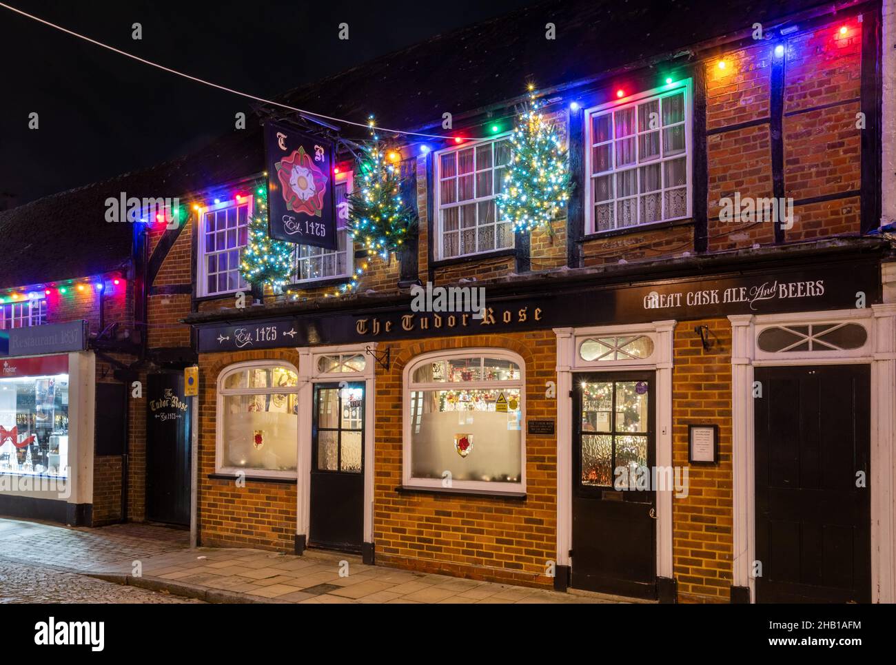 15th. Dezember 2021. Das Stadtzentrum von Romsey in Hampshire, Großbritannien, wurde mit farbenfrohen Weihnachtslichtern dekoriert und beleuchtet. Das Tudor Rose Pub aus dem 15th. Jahrhundert auf dem Maismarkt. Stockfoto
