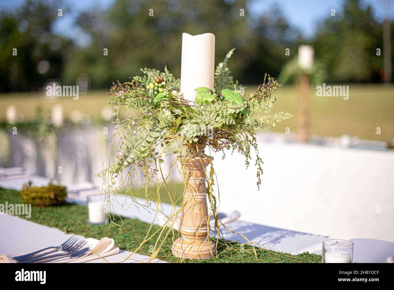 Kerzenständer aus Holz mit grünen Pflanzen in der Mitte des Tisches bei der Hochzeitsfeier im Freien Stockfoto