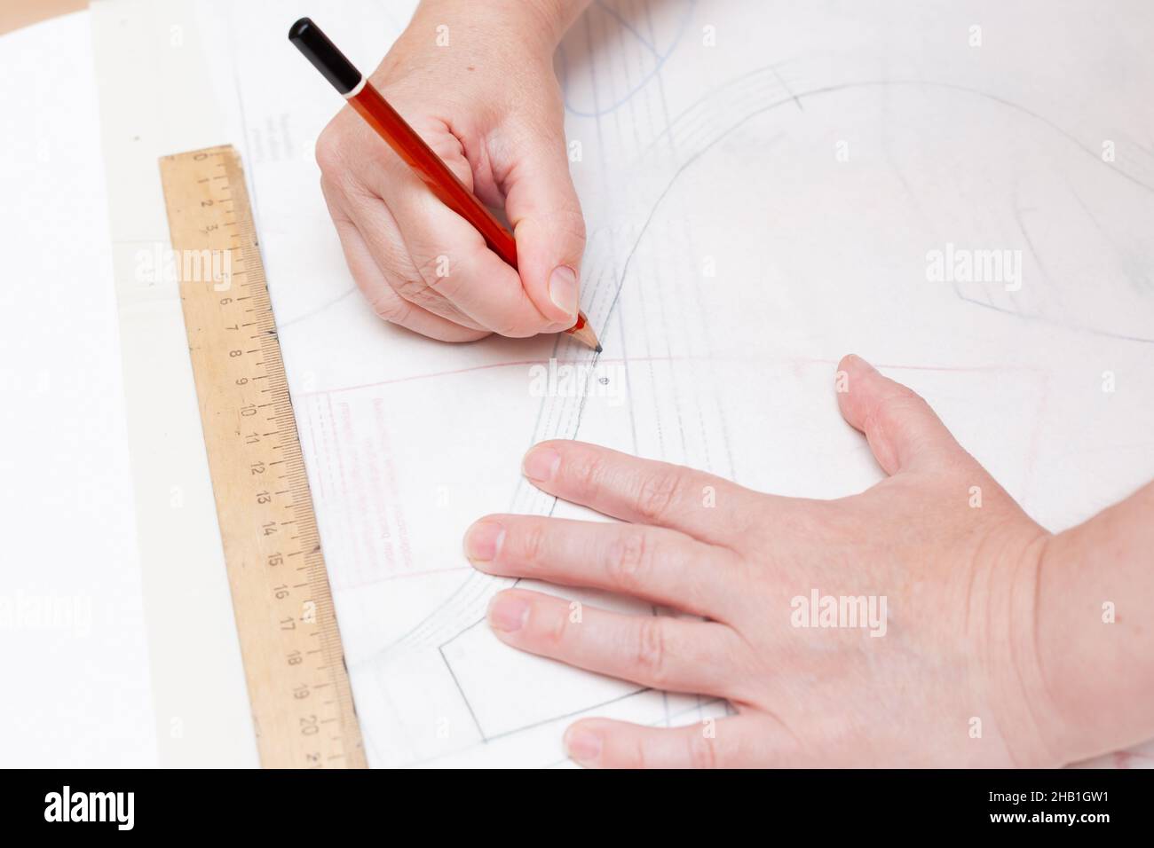 Weibliche Hände machen das Layout des Nähmusters auf Papier Stockfoto