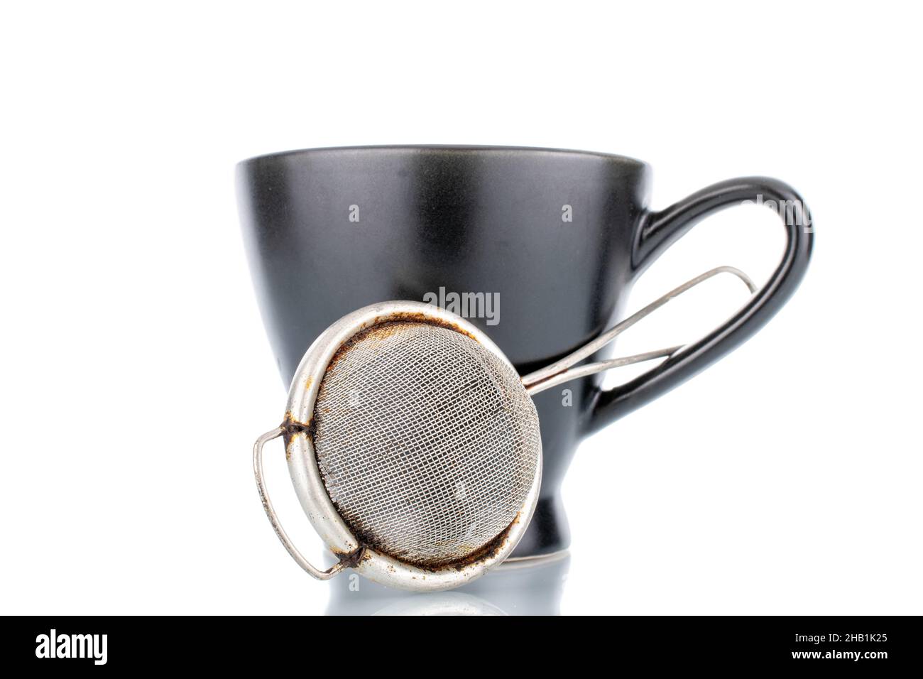 Ein Teesieb aus Metall und eine schwarze Keramikschale, Nahaufnahme, isoliert auf Weiß. Stockfoto