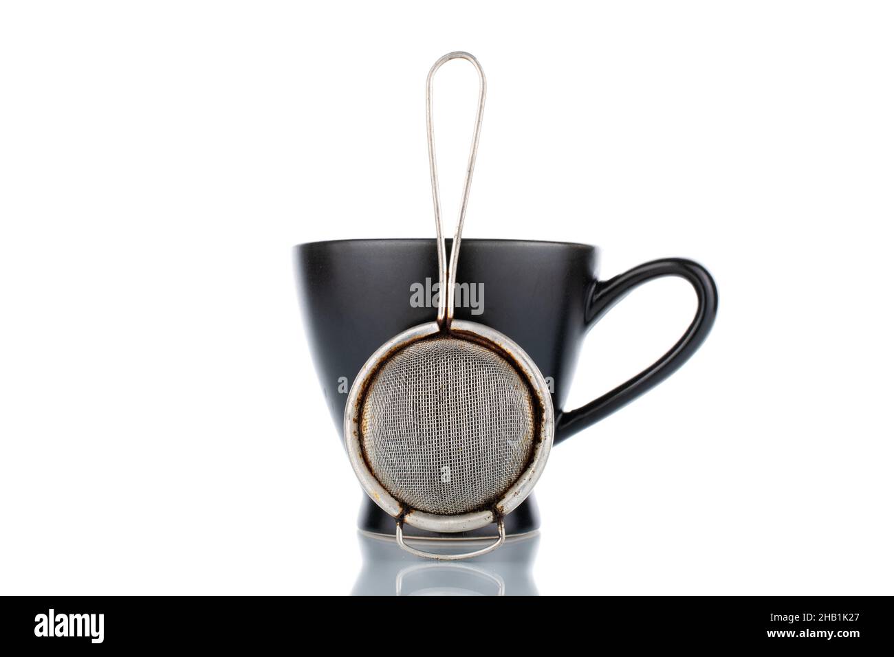 Ein Teesieb aus Metall und eine schwarze Keramikschale, Nahaufnahme, isoliert auf Weiß. Stockfoto