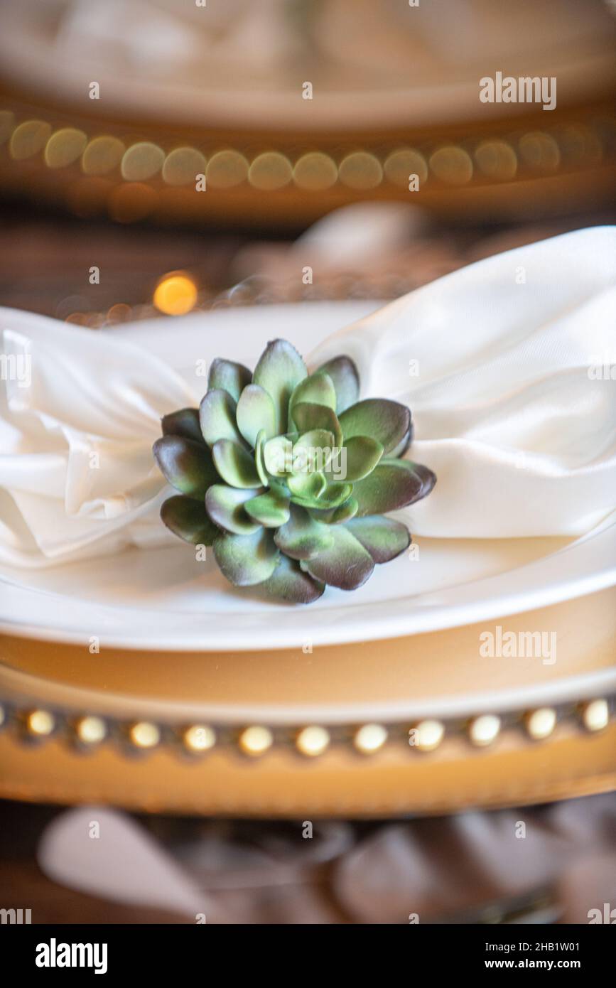 Serviette aus weißem Leinen, Blumennapkin-Ring auf goldenen Ladegeräten Stockfoto