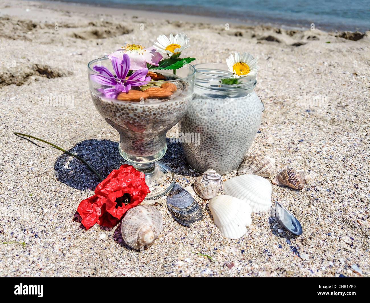 Nahaufnahme eines Chiasamen-Puddings mit Mandelmilch auf dem Hintergrund des Strandes Stockfoto