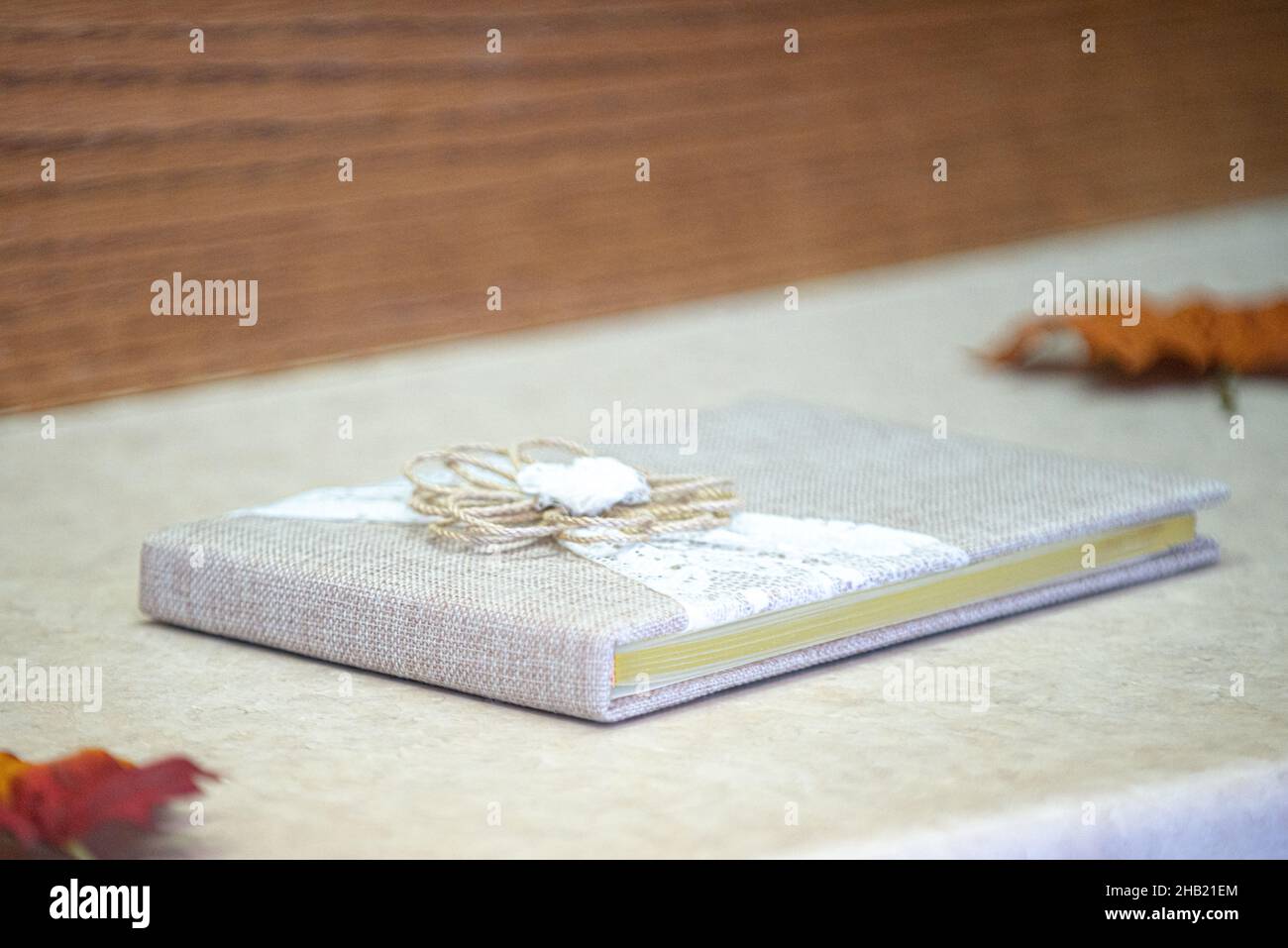 Grauer Eibengras und Spitze mit Schleife als Gäste-Schild im Buch bei der Herbsthochzeit Stockfoto