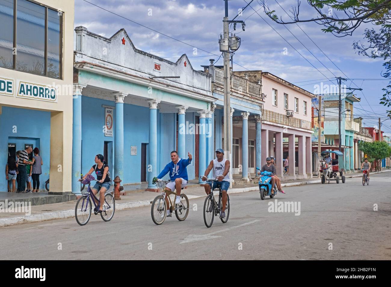 Kubaner fahren mit dem Fahrrad durch die Straße mit bunten Gebäuden in der Stadt Ciego de Ávila auf der Insel Kuba, Karibik Stockfoto