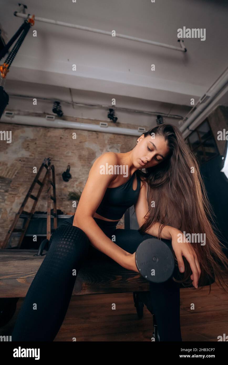 Junge Frau pumpt die Muskeln mit einem Arm Hantel heben. Stockfoto