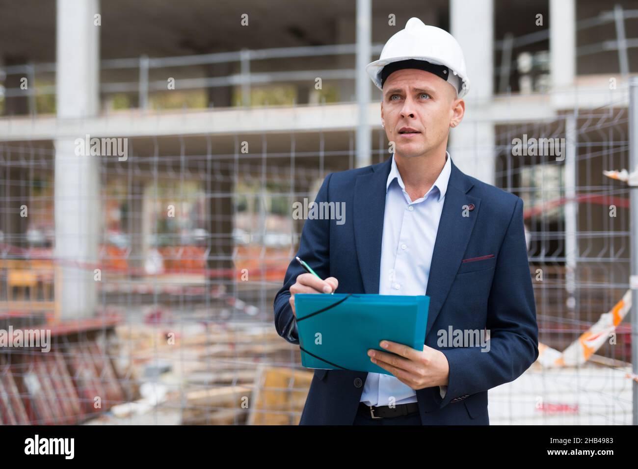 Männlicher Ingenieur überprüft den Arbeitsprozess auf der Baustelle Stockfoto