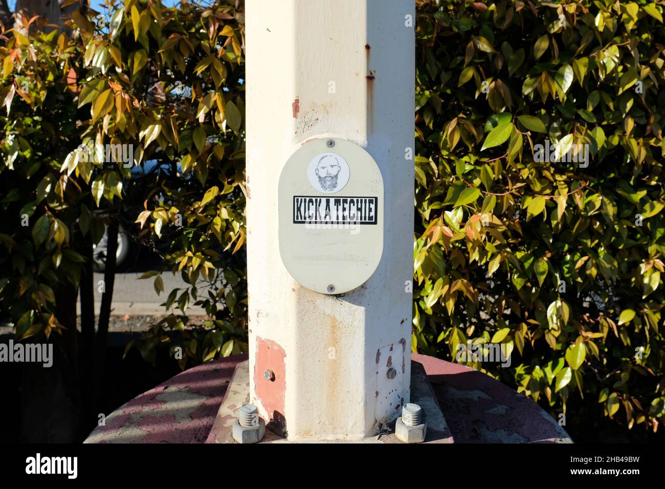 Anti-Techie-Aufkleber am Fuß eines Lichtpfostens auf einem Parkplatz in San Carlos, Kalifornien, der Feindseligkeit gegenüber Technikern in der Bay Area zum Ausdruck bringt. Stockfoto